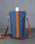 Blue bag with brown strap on a gray surface against a gray background