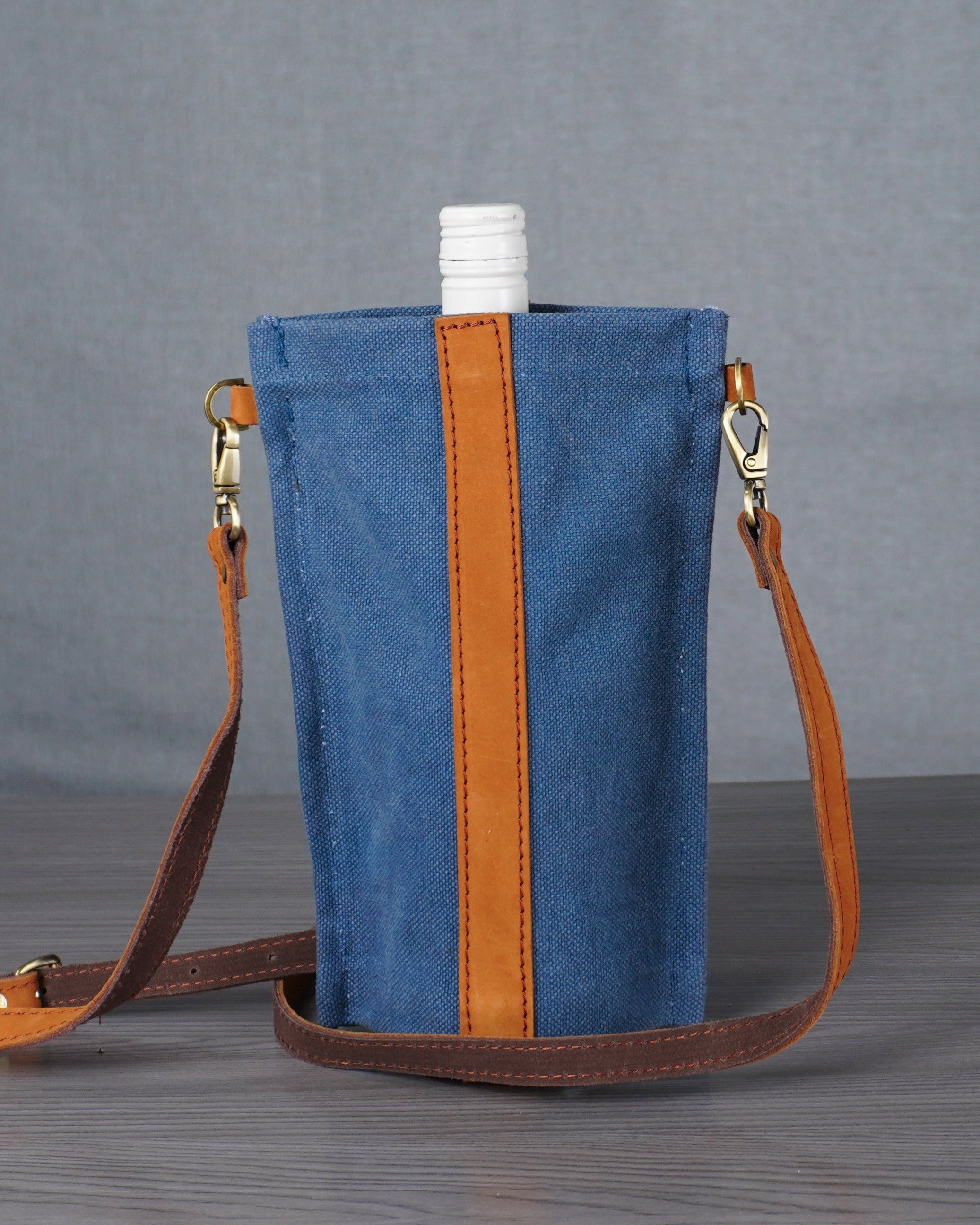 Blue bag with brown strap on a gray surface against a gray background
