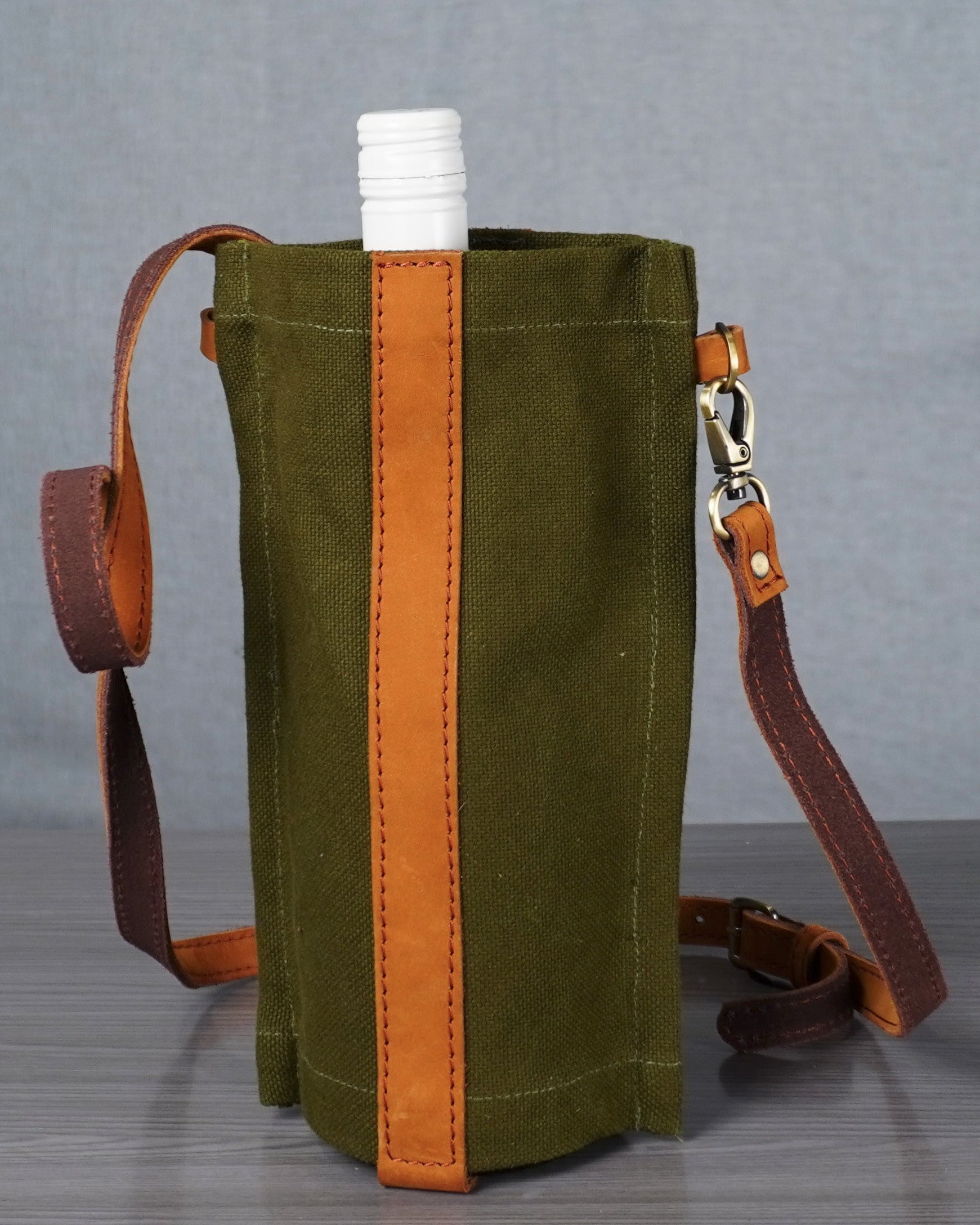 Green canvas bag with brown accents and a strap on a gray background