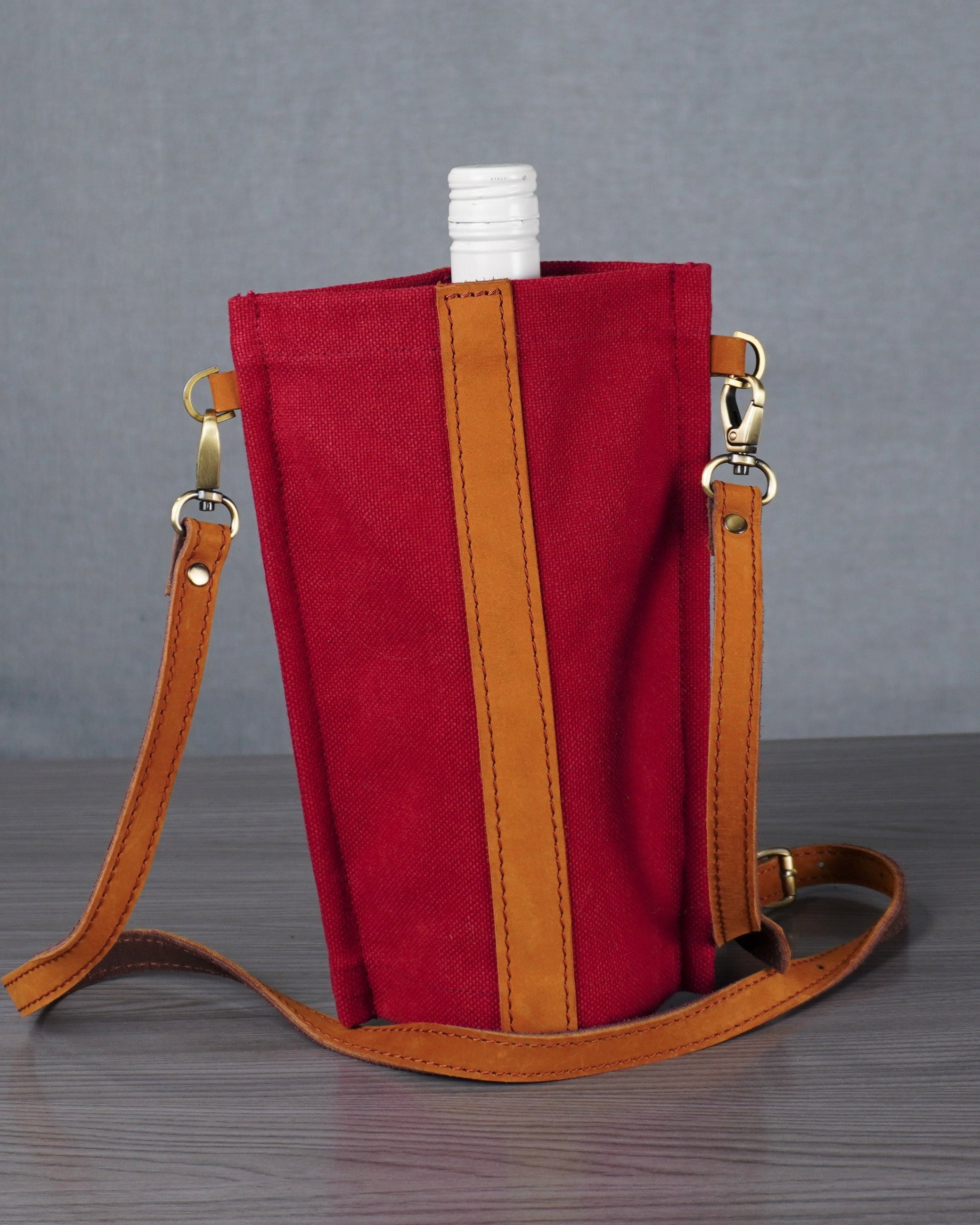 Red bag with a brown strap on a gray surface against a gray background